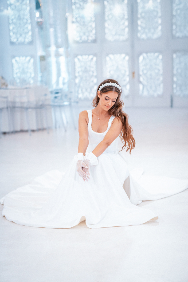 Булка в бяла рокля седи на пода в светла тържествена зала | Bride in a white dress sitting on the floor in a bright ballroom
