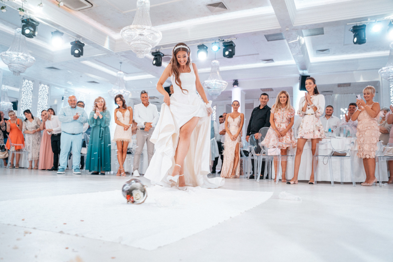 Булка рита менче с цветя пред погледите на гостите в ресторант | Bride kicking a traditional copper vessel (menche) with flowers in a restaurant