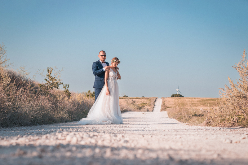 Младоженци стоят на бял полски път сред природата | Bride and groom standing on a white dirt road in nature